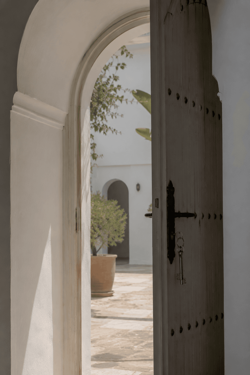 Arched doorway with keys opening onto a sunlit courtyard